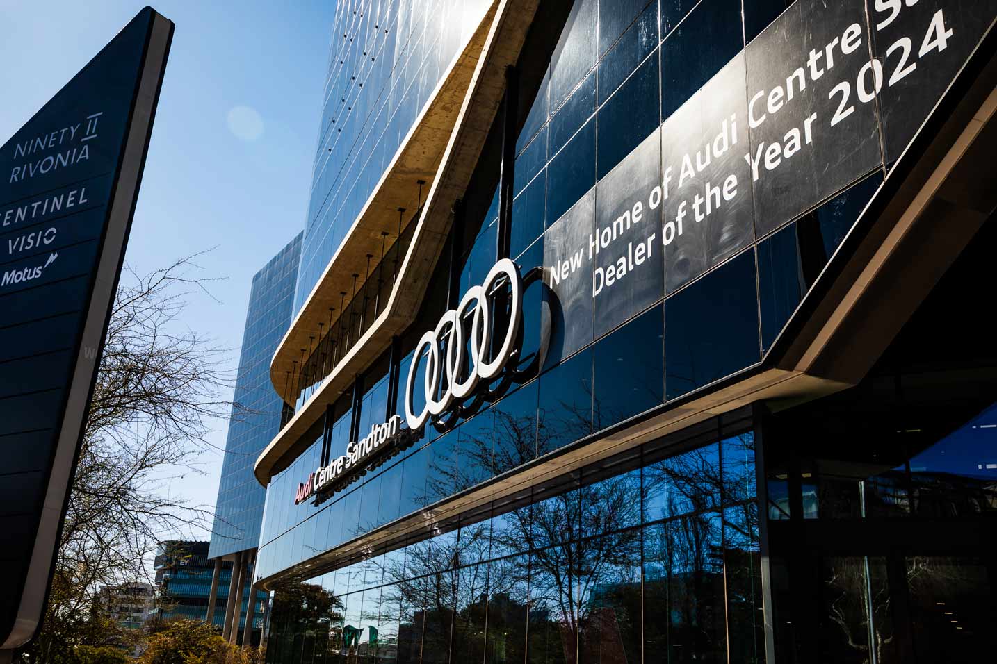 Audi Centre Sandton: the glazed dealership facade with the Audi rings and Dealer of the Year 2024 signage.