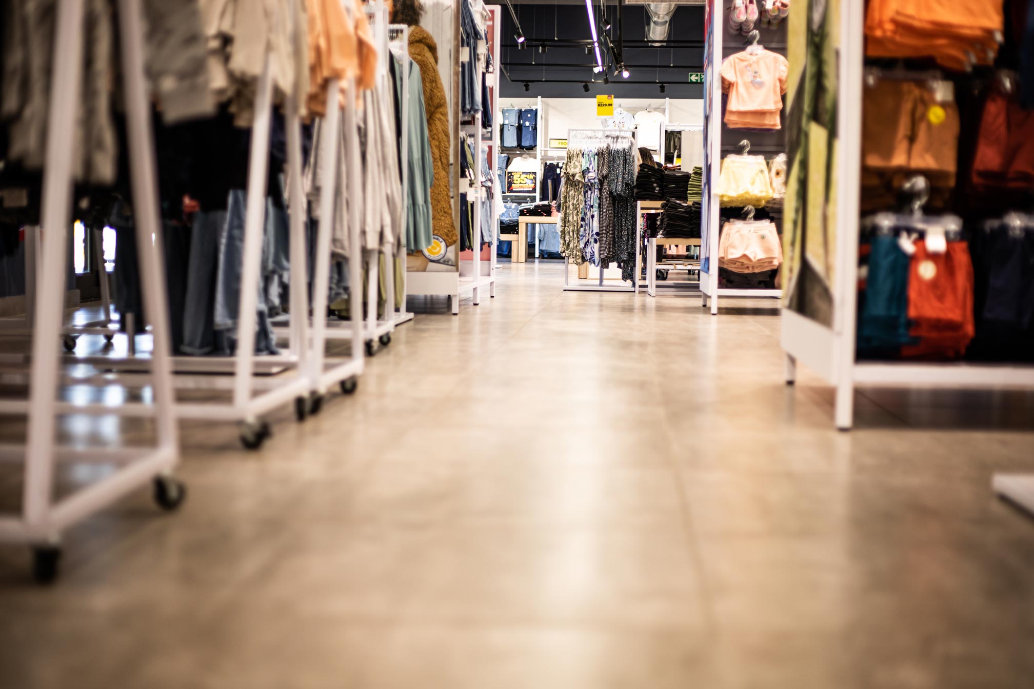 Crowthorne: the completed retail interior, looking down the aisle between clothing rails to the timber look floor.