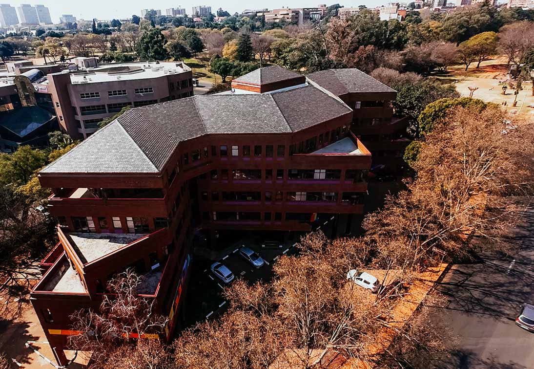 Hillside: aerial view of the red brick multi storey office block and its tiled roof, with the Gauteng skyline behind.